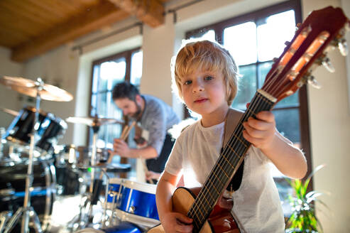 Porträt eines glücklichen kleinen Jungen mit seinem Vater, der zu Hause Schlagzeug und Gitarre spielt. - HPIF13515