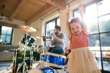 Porträt von glücklichen kleinen Kindern mit Vater zu Hause, die Schlagzeug spielen. - HPIF13518