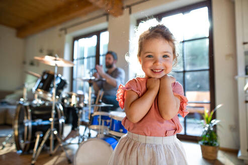 Porträt eines glücklichen kleinen Mädchens in einem Haus, das in die Kamera schaut. - HPIF13519