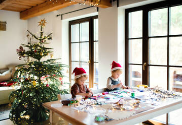 Porträt eines glücklichen kleinen Mädchens und eines Jungen, die zu Weihnachten zu Hause sind und Bilder malen. - HPIF13535