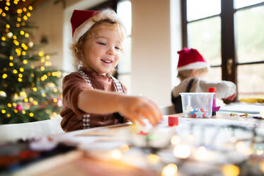 Porträt eines glücklichen kleinen Mädchens und eines Jungen, die zu Weihnachten zu Hause sind und Bilder malen. - HPIF13538