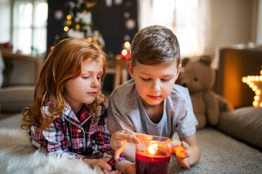 Small girl lying and sleeping on sofa indoors at Christmas, holding candle. - HPIF13603