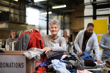 Portrait of volunteers sorting out donated clothes in community charity donation center. - HPIF13620