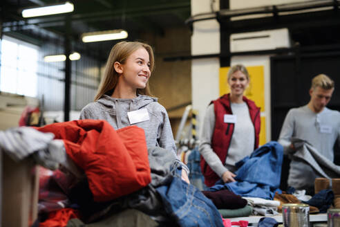 Porträt von Freiwilligen, die gespendete Kleidung im Spendenzentrum der Gemeinde aussortieren. - HPIF13623