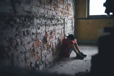 Sad and disappointed teenagers boy sitting on chair indoors in abandoned building. - HPIF13677