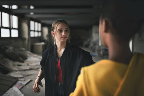 Verängstigtes Teenager-Mädchen, das in einem verlassenen Gebäude von einem Schläger angegriffen wird, Konzept der Bandengewalt und des Mobbings. - HPIF13682