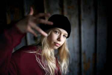 Front view portrait of blond teenager girl standing indoors in abandoned building. - HPIF13689