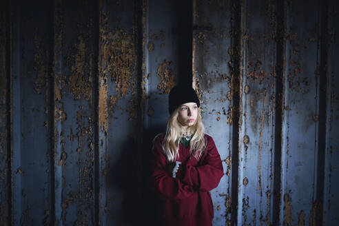 Frontansicht Porträt eines blonden Teenagers, der in einem verlassenen Gebäude steht. - HPIF13690
