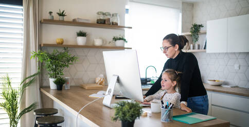 Woman with small daughter working indoors at home office, Corona virus and quarantine concept. - HPIF13707