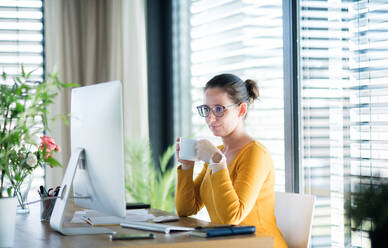 Frau mit Kaffee bei der Arbeit zu Hause im Büro, Corona-Virus und Quarantäne-Konzept. - HPIF13714