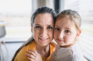 Front view of mother and child indoors at home, looking at camera. - HPIF13725