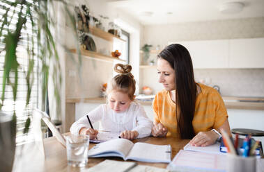 Mother and small daughter learning indoors at home, Corona virus and quarantine concept. - HPIF13726