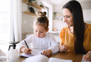 Mother and small daughter learning indoors at home, Corona virus and quarantine concept. - HPIF13727