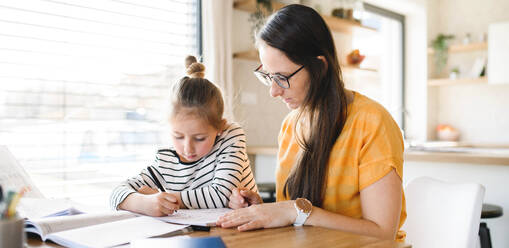 Mother and small daughter learning indoors at home, Corona virus and quarantine concept. - HPIF13729