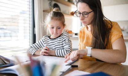 Mother and small daughter learning indoors at home, Corona virus and quarantine concept. - HPIF13730