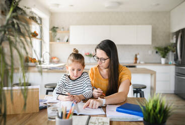 Mother and small daughter learning indoors at home, Corona virus and quarantine concept. - HPIF13732