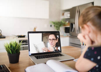 Small girl with laptop learning through internet indoors at home, Corona virus and quarantine concept. - HPIF13738