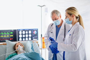 Doctors and infected patient in quarantine lying in bed in hospital, coronavirus concept. - HPIF13760