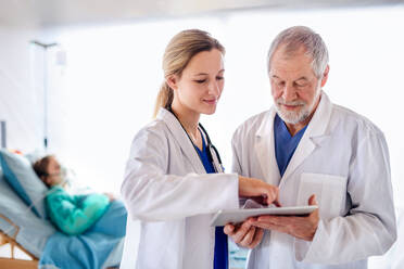 Ein Mann und eine Frau, die sich mit einem Tablet im Krankenhaus unterhalten, Konzept des Coronavirus. - HPIF13761