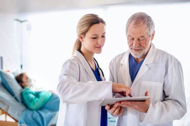 Man and woman doctors with tablet talking in hospital, coronavirus concept. - HPIF13761