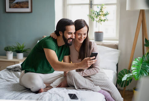 Ein glückliches Paar hält seine Liebe mit einem Selfie in der eigenen Wohnung fest - HPIF13775