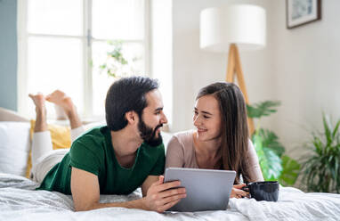 Happy young couple in love using tablet on bed indoors at home. - HPIF13777