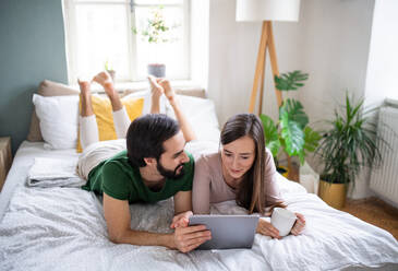 Happy young couple in love using tablet on bed indoors at home. - HPIF13778