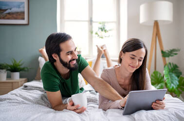 Happy young couple in love using tablet on bed indoors at home. - HPIF13779