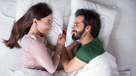 Draufsicht auf ein junges, verliebtes Paar, das zu Hause auf dem Bett liegt, Nahaufnahme. - HPIF13787