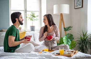 Glückliches, verliebtes junges Paar beim Frühstück auf dem Bett zu Hause. - HPIF13790
