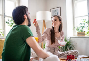 Happy young couple in love eating breakfast on bed indoors at home. - HPIF13792