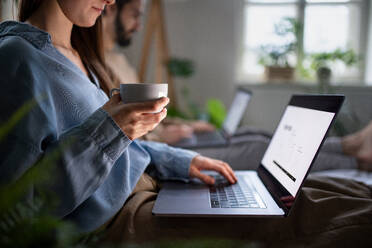 Unrecognizable young couple using laptops on bed indoors, home office in lockdown concept. - HPIF13799