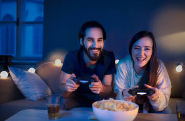 Glückliches, verliebtes junges Paar spielt zu Hause Videospiele. - HPIF13807