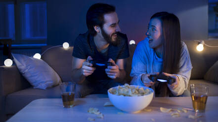 Happy young couple in love playing video games indoors at home. - HPIF13808