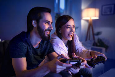 Glückliches, verliebtes junges Paar spielt zu Hause Computerspiele. - HPIF13810