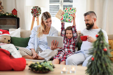 Familie mit kleiner Tochter zu Hause an Weihnachten, Videoanruf auf dem Tablet. - HPIF13819