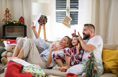 Familie mit kleiner Tochter zu Hause an Weihnachten, Videoanruf auf dem Tablet. - HPIF13820