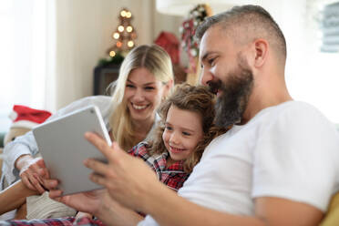Familie mit kleiner Tochter zu Hause an Weihnachten, Videoanruf auf dem Tablet. - HPIF13821