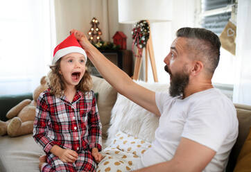 Porträt eines Vaters mit einer kleinen Tochter, die sich zu Weihnachten zu Hause amüsiert. - HPIF13823