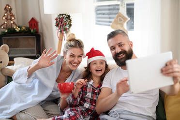 Familie mit kleiner Tochter zu Hause an Weihnachten, Videoanruf auf dem Tablet. - HPIF13824