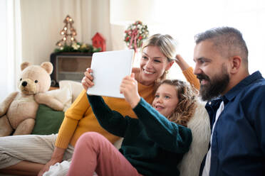 Family with small daughter indoors at home at Christmas, having video call on tablet. - HPIF13828