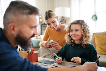 Eine glückliche Familie mit einer kleinen Tochter, die zu Weihnachten zu Hause ist und Weihnachtskarten bastelt. - HPIF13833