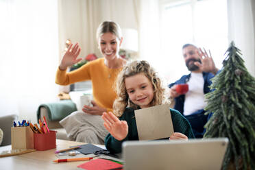 Family with small daughter indoors at home at Christmas, having video call on tablet. - HPIF13835