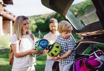 Family with small child going on cycling trip in countryside, putting things in car boot. - HPIF13944