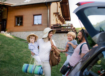 Vorderansicht einer Familie mit zwei kleinen Kindern, die ihr Auto für einen Ausflug in die Natur beladen. - HPIF13952