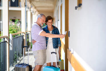 Älteres Ehepaar mit Gepäck vor der Wohnung im Urlaub, zurück zum normalen Konzept. - HPIF13984