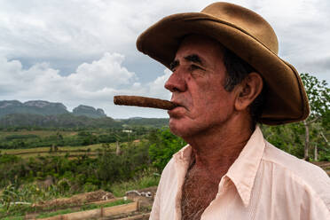 Tobacco plantation worker with cigar, on valley ridge, Vinales, Cuba, West Indies, Caribbean, Central America - RHPLF23917