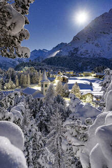 Vollmond über der schneebedeckten Chiesa Bianca inmitten von Wäldern, Maloja, Bergell, Engadin, Kanton Graubünden, Schweiz, Europa - RHPLF23945