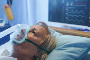 A close-up of covid-19 patient with oxygen mask in bed in hospital, coronavirus concept. - HPIF14001