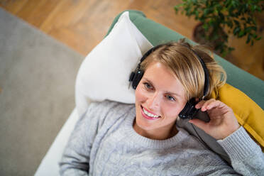 Top view portrait of woman with headphones relaxing indoors at home, mental health care concept. - HPIF14023
